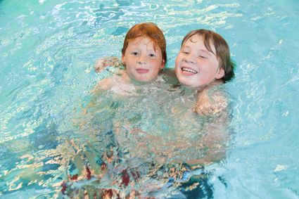 Zwembad Batenstein in Woerden, Groene Hart. Twee kinderen spelen en zwemmen samen in het binnenzwembad tijdens een gezinsuitje, met helder zwembadwater en recreatief zwemmen voor gezinnen en kinderen.