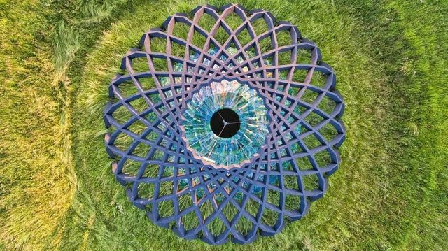 Een luchtfoto van een kunstzinnig bouwwerk in een groen veld.