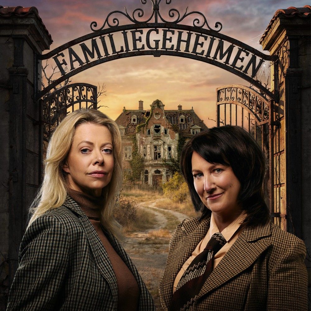 Foto van een blonde en donkere vrouw, ze staan voor een hek met daarin de letters 'Famiegeheimen' tussen hen in. Op de achtergrond is nog een verlaten, vervallen landhuis te zien.
