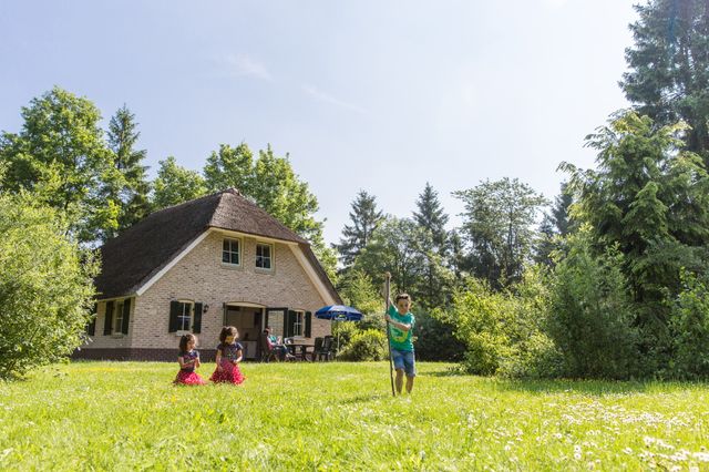 Kinderen spelen in de tuin voor een vakantiebungalow in Drenthe.