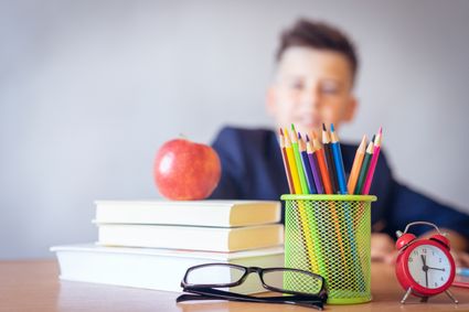 School desk with books, glasses and pencils.