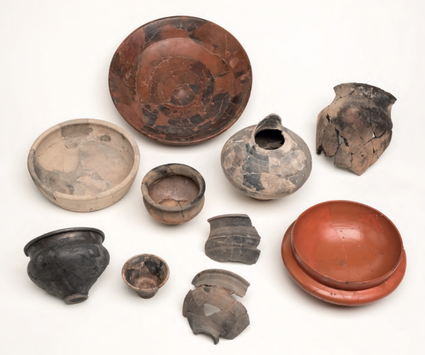 Verbrand en onverbrand aardewerk uit het graf in het centrum.