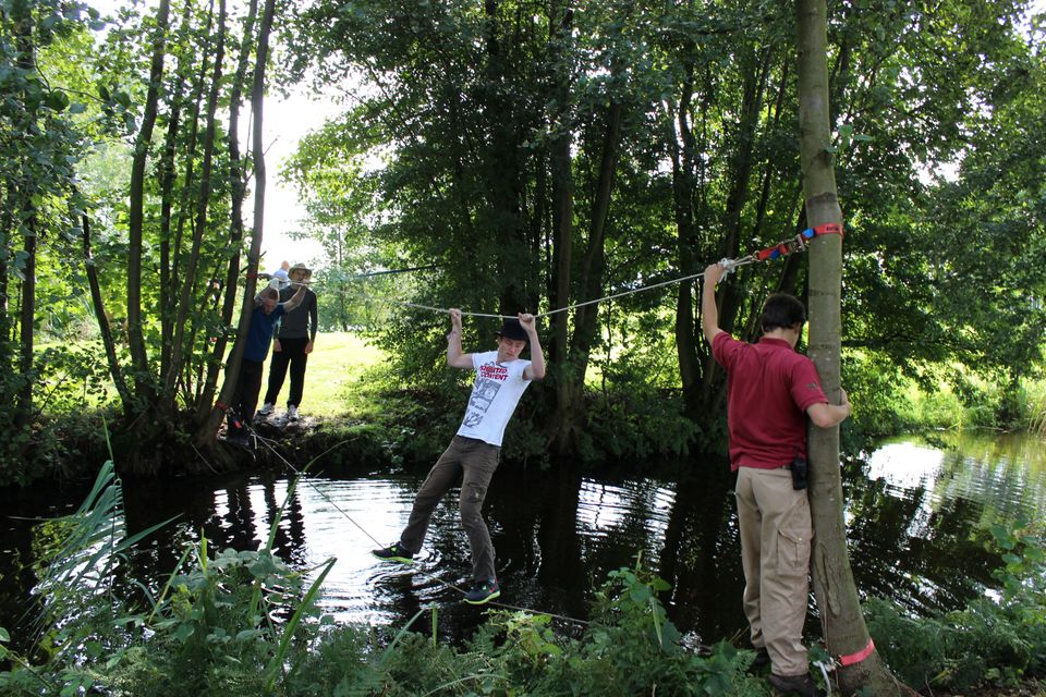 Groepsactiviteit Expeditie Kameryck bij Buitenplaats Kameryck in Kamerik, deelnemers steken via een touwparcours het water over tijdens een actief teamuitje in het Groene Hart