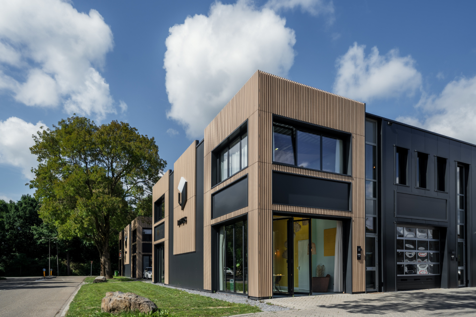 Een foto van de voorgevel van de locatie met een blauwe lucht met een aantal witte wolken.