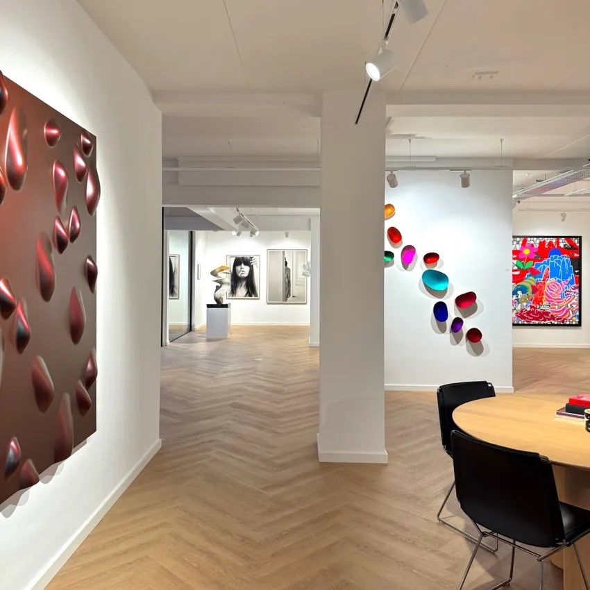 Overzicht van de galerie met rechts een tafel met stoelen en rondom aan de muren verschillende kunstwerken en beelden.