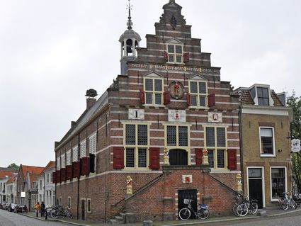 Historisch stadhuis van Oudewater met karakteristieke trapgevel, rood-witte luiken en bakstenen gevel, gelegen in het oude centrum van Oudewater.
