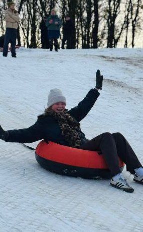 Een vrouw glijdt op een band van een besneeuwde heuvel af