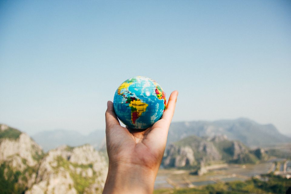 Holding a globe against the sky.