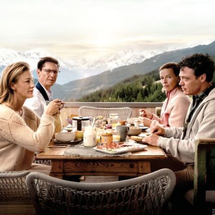 Foto van 2 echtparen aan een ontbijttafel met uitzicht op de besneeuwde Oostenrijkse Alpen.