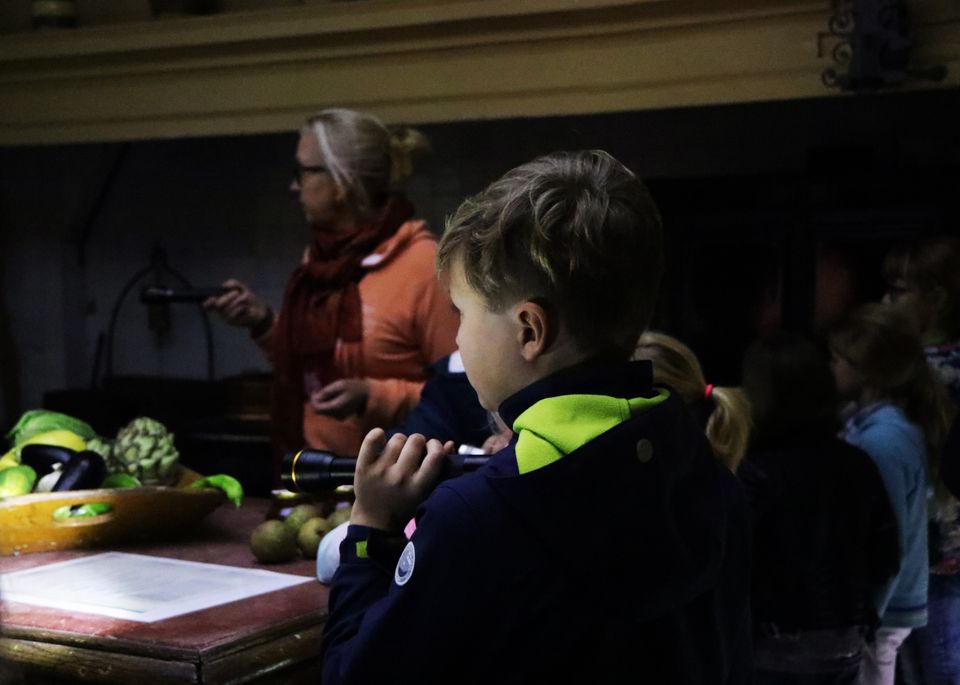 Kinderen zijn samen met een begeleider op zaklampentocht in Kasteel Amerongen
