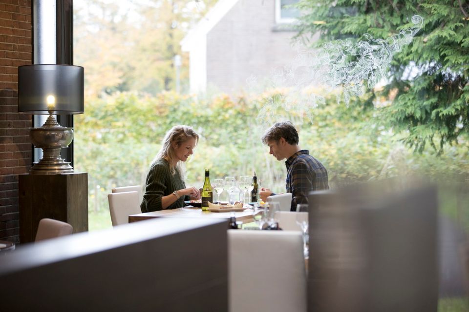 Een stel zit aan een tafeltje bij het raam te dineren.