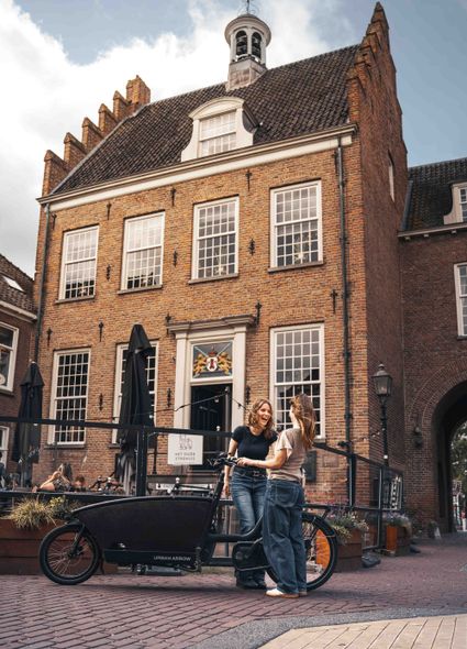 Historisch stadhuis Het Oude Stadhuis Montfoort, Groene Hart, bezoekers met fiets op het sfeervolle plein voor het monumentale stadhuis in de historische binnenstad.