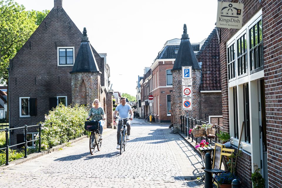 Historische stadspoort in IJsselstein, provincie Utrecht, Groene Hart, met twee fietsers tussen de oude bakstenen poorttorens en monumentale gevels in de binnenstad.