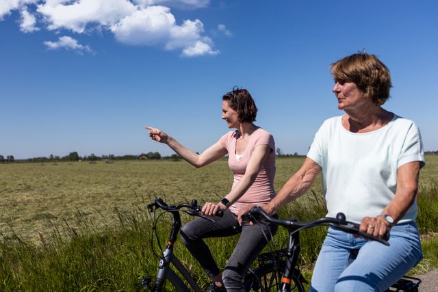 Twee vrouwen die fietsen door groene weilanden.