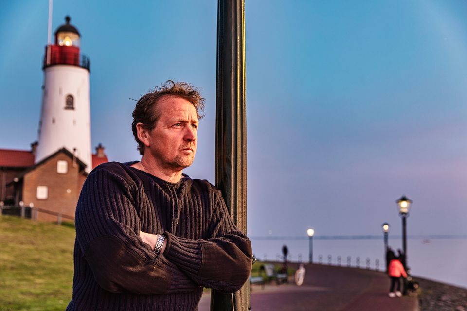 Man bij vuurtoren in de schemering van de avond op Urk in Flevoland