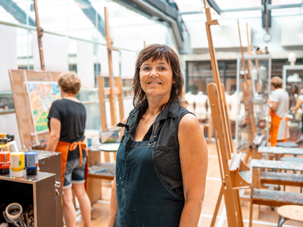 UITvergroot een vrouw die tussen schilderende mensen staat bij De Vak