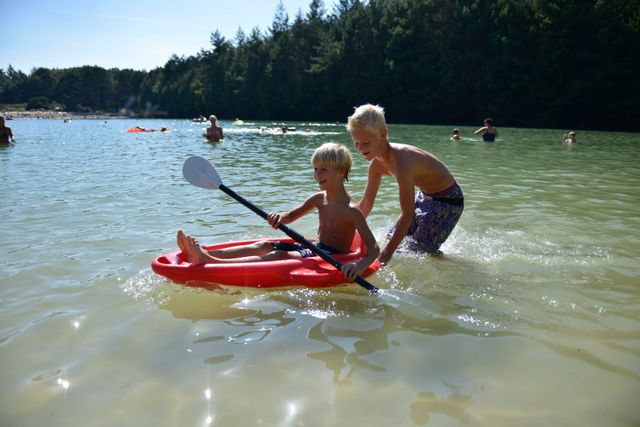 Jongens spelen met een kleine kajak in het water.