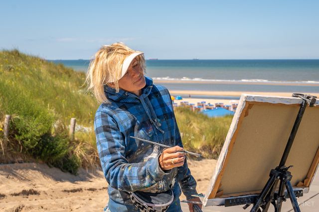 Kunstenares Anna Pavlova schildert buiten in de duinen tijdens Katwijk en Plein Air, met de Noordzee op de achtergrond.