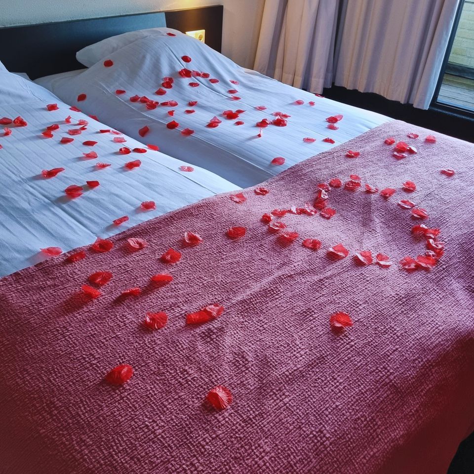 Een bed met daarop rozenblaadjes in de vorm van een hart bij Sporthotel Iselmar in Lemmer.