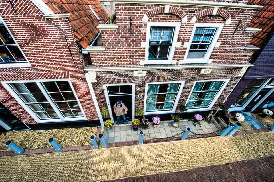 Bovenaanzicht van een woning waar een man in de deuropening staat