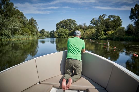 Man zit voorop een boot tijdens een vaartocht door de Randmeren in Flevoland