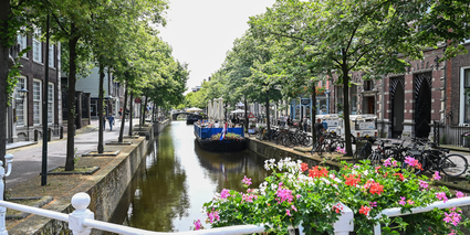 Kijkje op de grachten in Delft met een gezellige terrasboot in de zomer