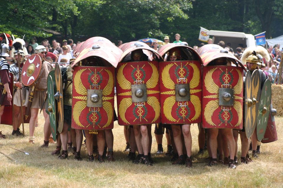 Testudo formatie: opgeheven schilden schermen een groep mannen af.