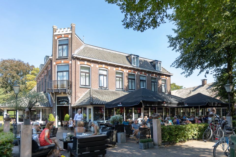 Een terras vol mensen bij een hotel restaurant.