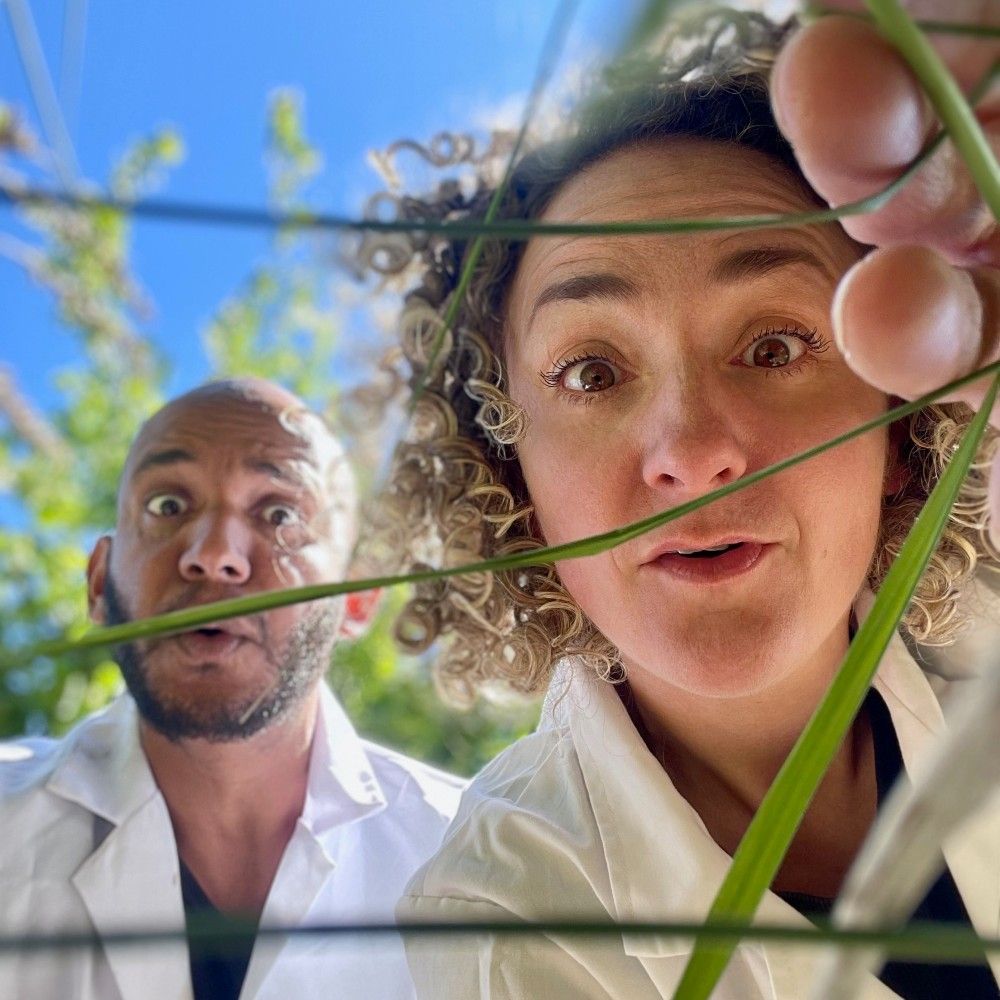 Foto van het gezicht van een man en een vrouw buiten in het gras die verwonderd, zoekend kijken.