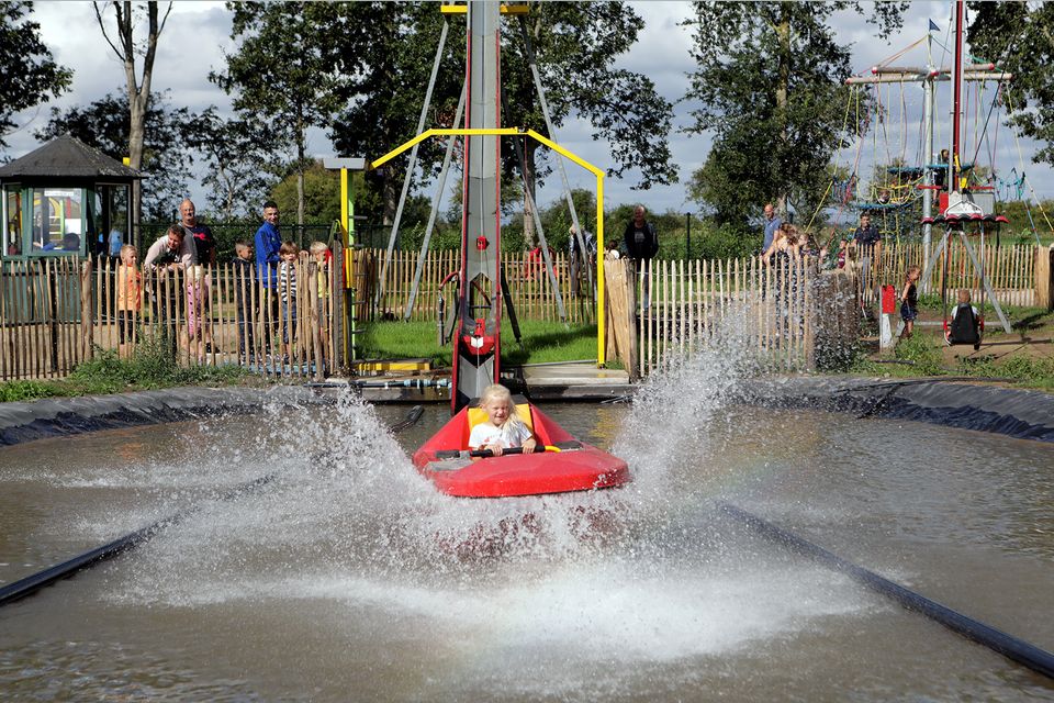 een meisje plonst in het water in een rood bootje