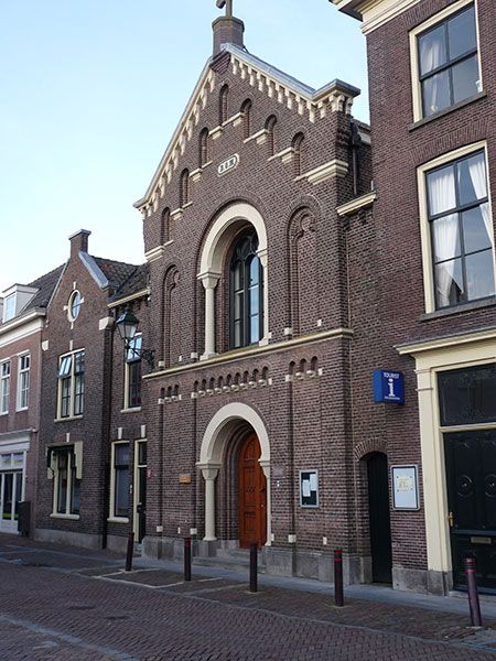Kerkgebouw, Oud Katholieke Kerk, Oudewater, Groene Hart. Historische bakstenen kerkgevel in de binnenstad met entree, hoge boogramen en VVV-informatiepunt naast de kerk.