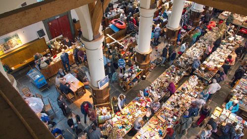 Een rommelmarkt in een kerk met veel mensen