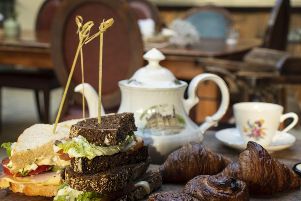 Een ouderwetse Engelse theepot en theekopjes, sandwiches en scones.