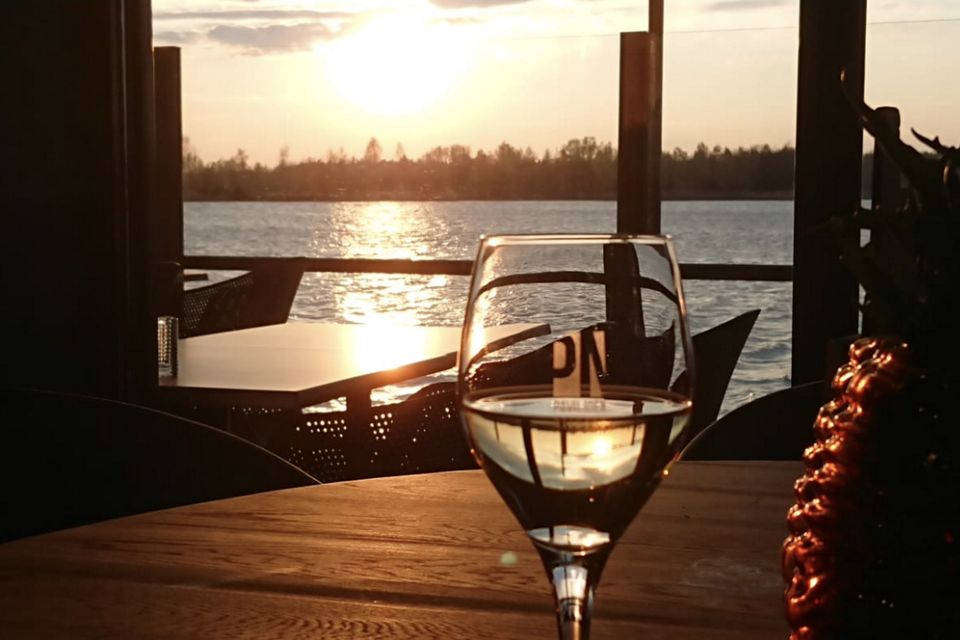 Een glas wijn op het terras met ondergaande zon.