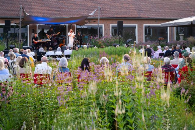 Publiek bekijkt theatervoorstelling in de museumtuin van Singer Laren.