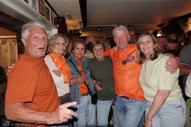 Horeca-evenement Koningsnacht in Woerden, Groene Hart, groep feestvierders in oranje kleding met drankjes in de hand tijdens het gezellige oranjefeest in een druk café in de binnenstad.