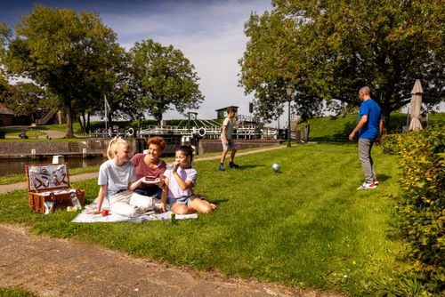 Gezin picknickt bij Benedensas, op de achtergrond spelen vader en zoon voetbal.