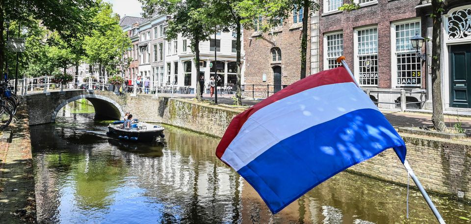 Grachten van Delft met een bootje in de zomer en de nederlandse vlag