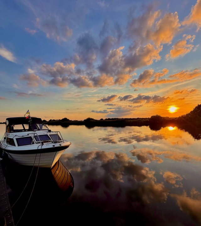 Een boot in het water bij ondergaande zon.