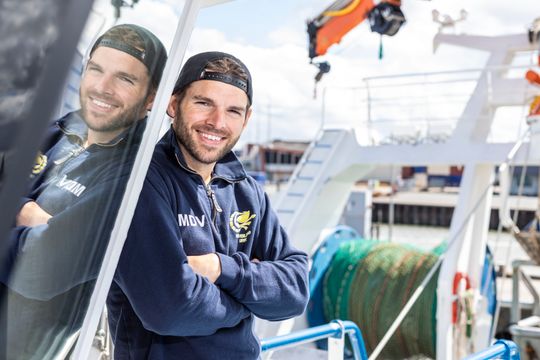 Een lachende visser op een schip in de haven van Flevoland