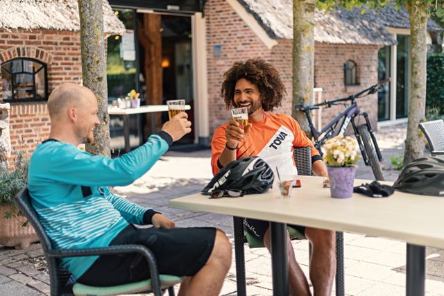 Na een stevige MTB-rit in de Drentse natuur, genieten 2 vrienden op het terras van een welverdiend biertje.