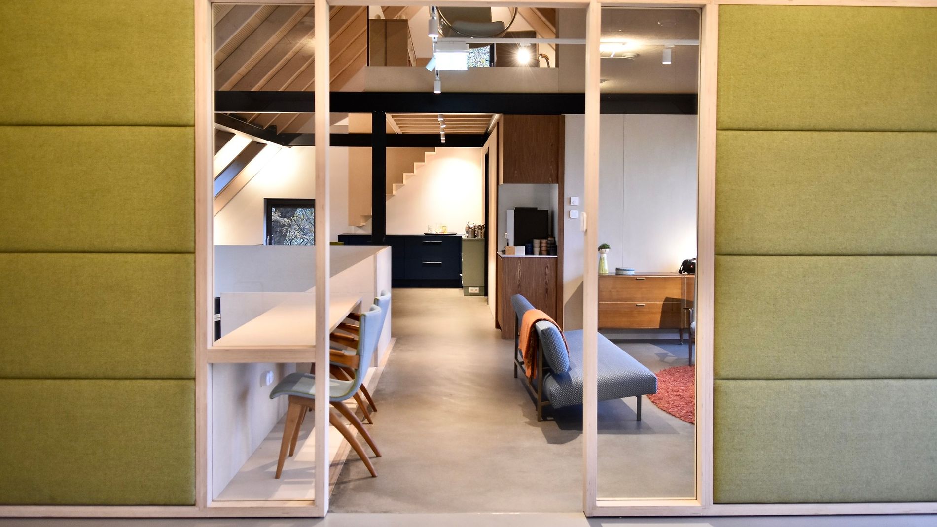 Inkijk in een ruimte onder een schuin dak met bankjes en tafel met stoelen.