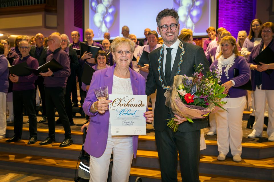 Locoburgemeester Martijn Kroonen reikt de Bokaal der Gemeente uit aan het Maassluise koor Sing for Joy tijdens het lustrumconcert op 22 november 2024. Het koor wordt geëerd voor haar 55 jaar lange inzet en betekenisvolle bijdrage aan het culturele leven van Maassluis