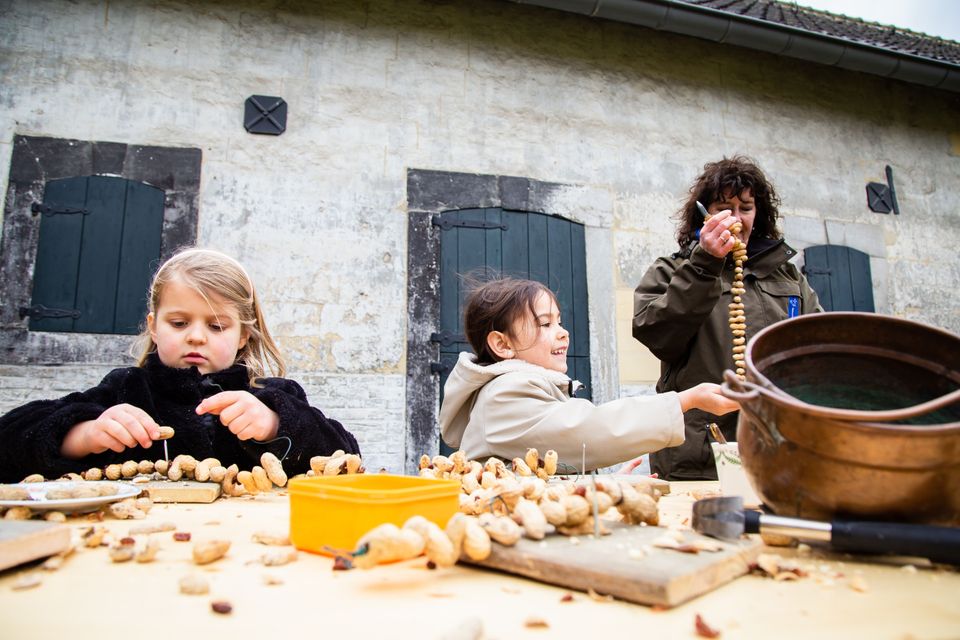 Kinderen rijgen pinda's aan een touw.