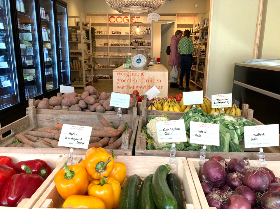Winkel Oogst Shop Woerden, provincie Utrecht, Groene Hart, houten kisten met aardappelen, wortels, bananen en bloemkool in een duurzame streekwinkel waar klanten lokale producten uitzoeken.