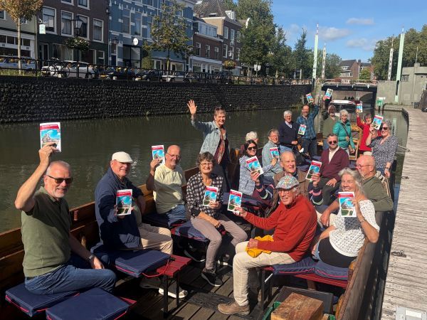 Een groep mensen in het Romeinse schip in Utrecht met in hun hand de nieuwe Wandelgids van Wandelnet over het Romeinse Limespad.