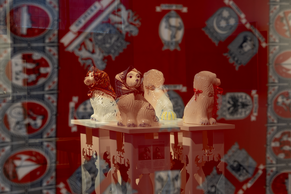 Tentoonstelling Bloed, zweet & tranen – De wereld van de zakdoek in Stadsmuseum Woerden, Groene Hart. Vitrines met keramische hondbeelden voorzien van kleurrijke zakdoeken, onderdeel van een museumexpositie over de geschiedenis en cultuur van de zakdoek.