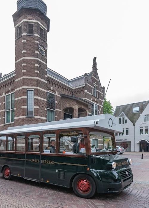 Foto van donkergroen treintje (de Parel Espress) voor het oude raadhuis van Oisterwijk.