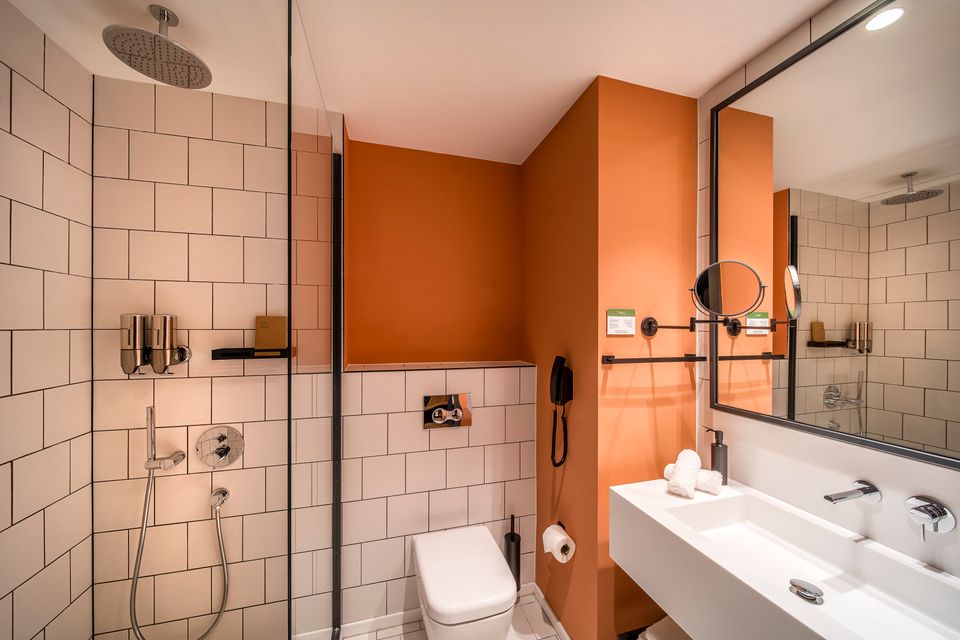 Foto van een moderne badkamer met wit sanitair en lichthouten kasten.