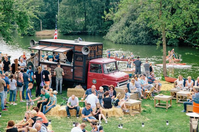 Een foodtruck aan het water waar mensen omheen staan tijdens een festival.